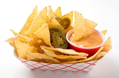 A basket of chips and salsa with jalapenos.