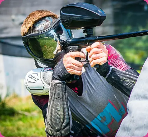 A man holding a paintball gun while wearing a helmet.