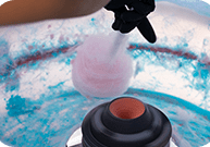 A person is pouring cotton candy into an ice cream maker.